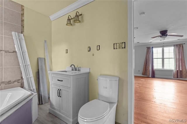bathroom featuring a ceiling fan, crown molding, wood finished floors, a bath, and toilet