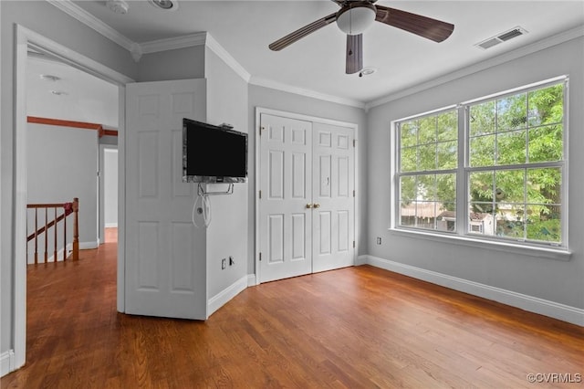 unfurnished bedroom featuring wood finished floors, baseboards, a closet, crown molding, and a ceiling fan