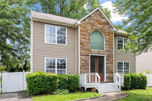 back of property featuring stone siding and fence