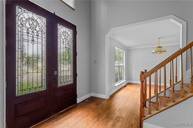 entrance foyer with wood finished floors, stairway, french doors, baseboards, and crown molding
