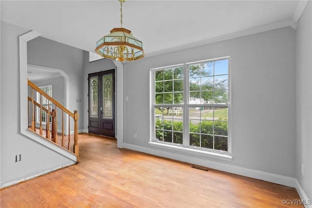foyer entrance featuring baseboards, crown molding, stairway, a chandelier, and wood finished floors