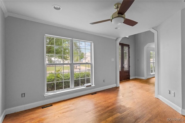 unfurnished room with ornamental molding, baseboards, arched walkways, wood finished floors, and recessed lighting