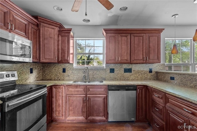 kitchen with stainless steel appliances, a sink, a ceiling fan, decorative light fixtures, and tasteful backsplash