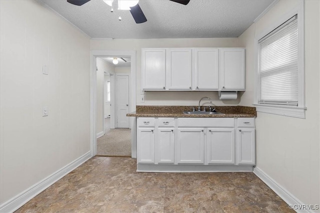 kitchen featuring a sink, dark countertops, ceiling fan, and white cabinets