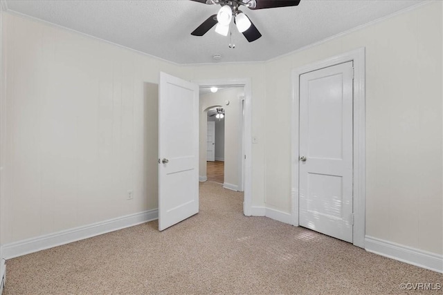 unfurnished bedroom featuring crown molding, a ceiling fan, baseboards, and light carpet