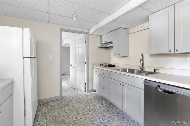 kitchen with a sink, a paneled ceiling, freestanding refrigerator, stainless steel dishwasher, and under cabinet range hood