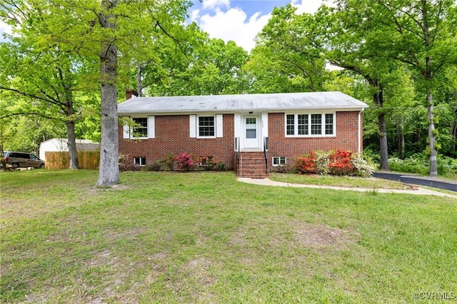 ranch-style home featuring brick siding, a chimney, a front yard, and entry steps