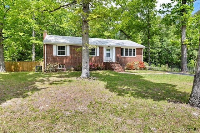 single story home with brick siding, fence, a chimney, and a front yard