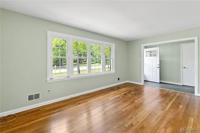 empty room with baseboards, wood finished floors, and visible vents