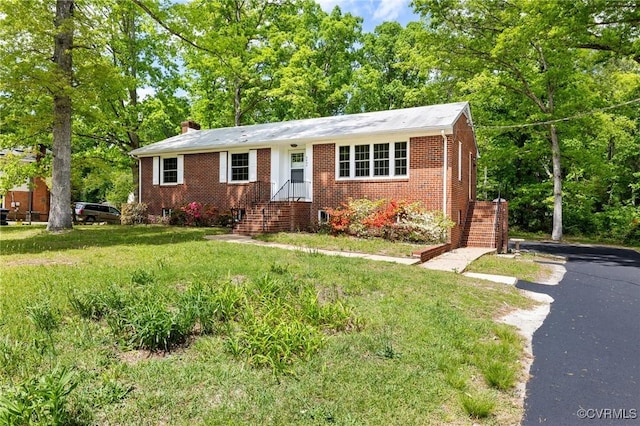 ranch-style home with brick siding, a chimney, and a front yard