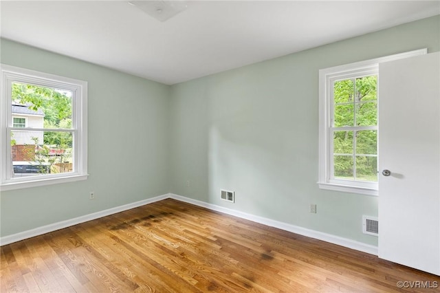 unfurnished room with visible vents, baseboards, and wood finished floors