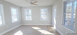 spare room featuring baseboards, a wealth of natural light, and wood finished floors