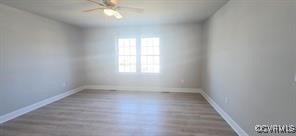empty room featuring ceiling fan, baseboards, and wood finished floors