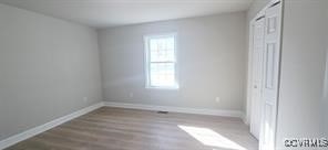 unfurnished bedroom featuring baseboards, wood finished floors, and a closet