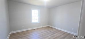 empty room with baseboards and wood finished floors