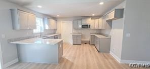 kitchen with light wood-style floors, light countertops, a peninsula, stainless steel microwave, and recessed lighting