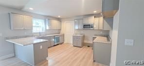 kitchen with recessed lighting, a peninsula, wall oven, and stainless steel microwave