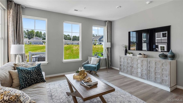 living room featuring baseboards, visible vents, and wood finished floors