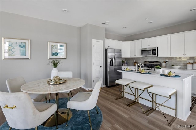 kitchen featuring light countertops, tasteful backsplash, stainless steel appliances, and wood finished floors
