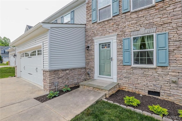 property entrance featuring an attached garage, driveway, and stone siding