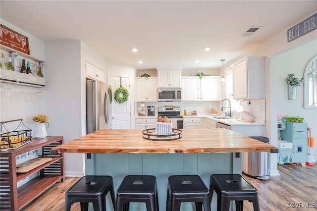 kitchen featuring a sink, appliances with stainless steel finishes, wooden counters, and light wood-style flooring