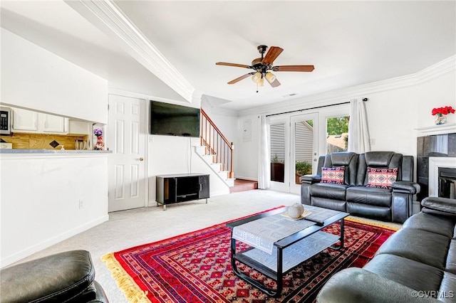carpeted living area featuring crown molding, french doors, a ceiling fan, baseboards, and stairway