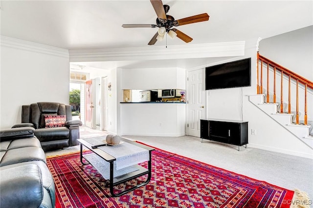 living area featuring carpet flooring, a ceiling fan, baseboards, ornamental molding, and stairway
