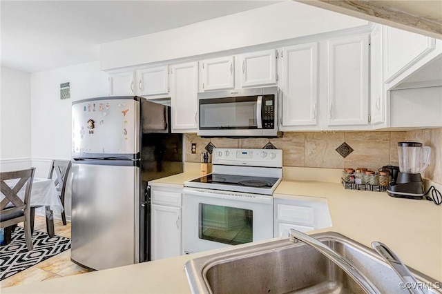 kitchen with a sink, light countertops, white cabinets, and stainless steel appliances