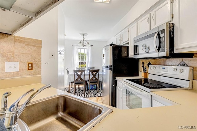 kitchen with white electric stove, a sink, white cabinets, stainless steel microwave, and a notable chandelier