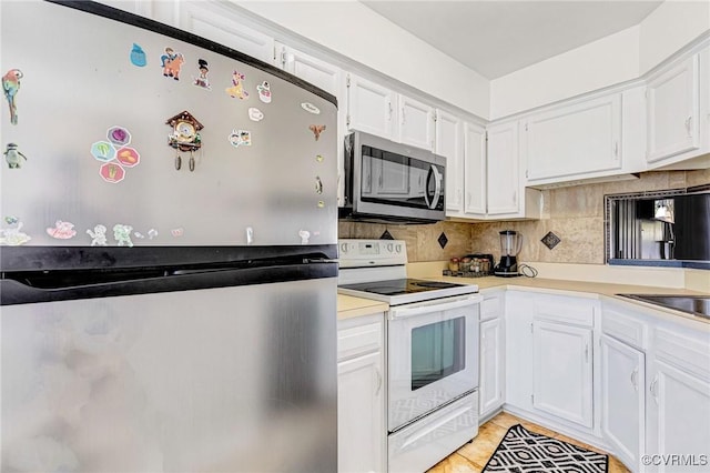 kitchen with light countertops, decorative backsplash, white cabinets, and stainless steel appliances