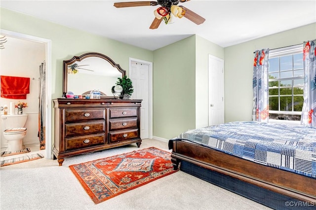 bedroom with baseboards, ensuite bathroom, carpet flooring, and ceiling fan