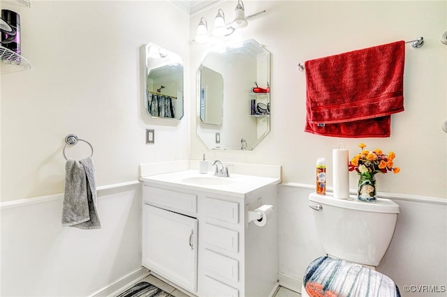 bathroom featuring vanity, ornamental molding, baseboards, and toilet