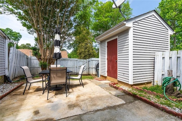 view of patio with an outdoor structure, a fenced backyard, a storage unit, and outdoor dining space
