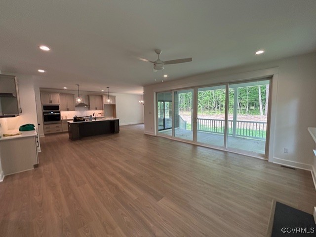 9107 Terroir Ln, New Kent, VA 23124 - unfurnished living room featuring ceiling fan, recessed lighting, healthy amount of natural light, and wood finished floors