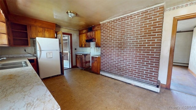 kitchen featuring open shelves, a sink, brown cabinetry, freestanding refrigerator, and a baseboard radiator