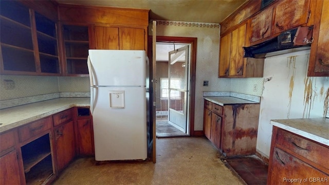 kitchen featuring decorative backsplash, brown cabinetry, open shelves, light countertops, and freestanding refrigerator