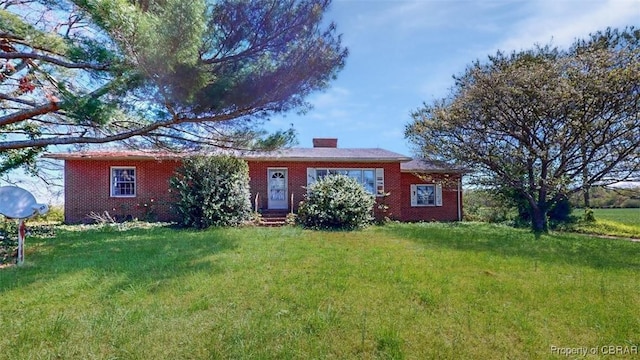ranch-style house featuring brick siding, a chimney, a front yard, and entry steps
