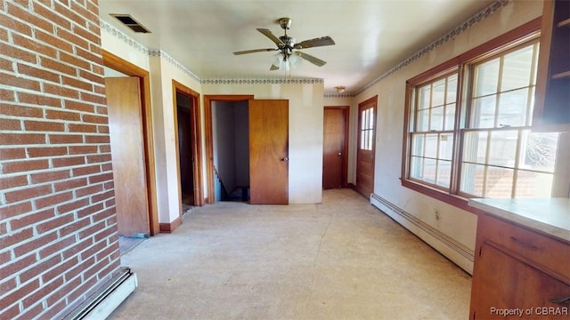 interior space featuring baseboards, a baseboard heating unit, brick wall, and visible vents