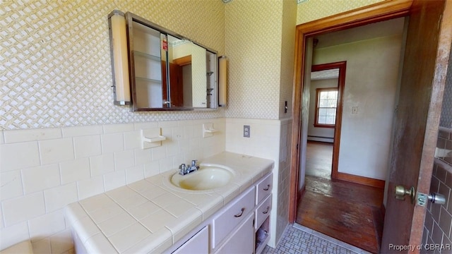 bathroom featuring wainscoting, vanity, wallpapered walls, tile walls, and a baseboard radiator