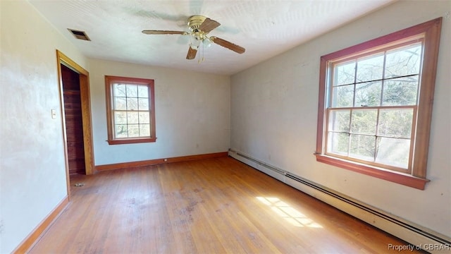 empty room with ceiling fan, light wood-style flooring, baseboards, a baseboard radiator, and visible vents