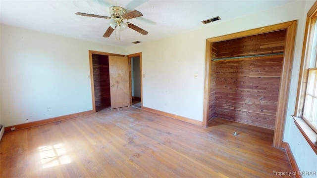 unfurnished bedroom featuring baseboards, a ceiling fan, wood finished floors, and visible vents