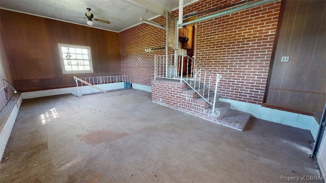 interior space with a ceiling fan, brick wall, and wooden walls