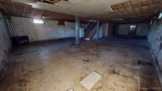 basement with a wood stove, stairs, tile patterned floors, and washer / dryer