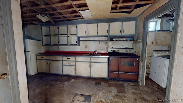 kitchen with freestanding refrigerator, dark countertops, washer / clothes dryer, range, and exhaust hood