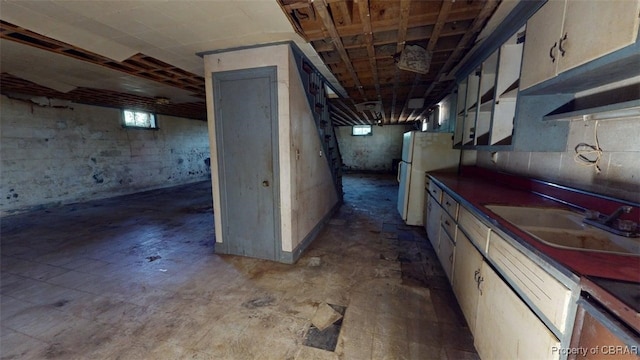 below grade area with a sink and freestanding refrigerator