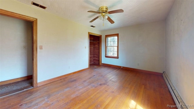 unfurnished room with visible vents, wood finished floors, baseboards, ceiling fan, and a baseboard radiator