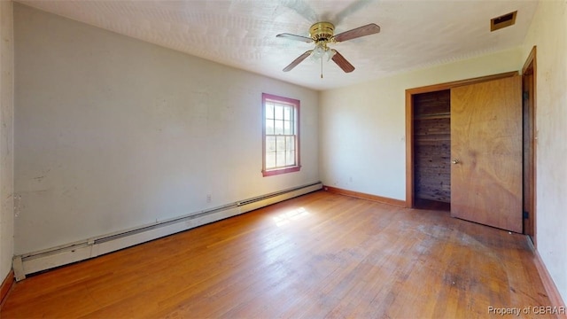 unfurnished bedroom with baseboards, wood finished floors, a baseboard radiator, visible vents, and a closet