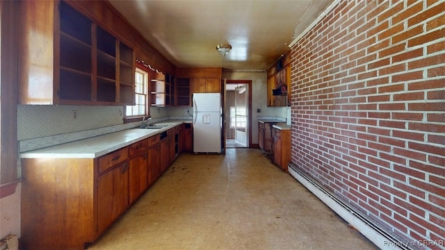 kitchen featuring freestanding refrigerator, open shelves, baseboard heating, light countertops, and a sink