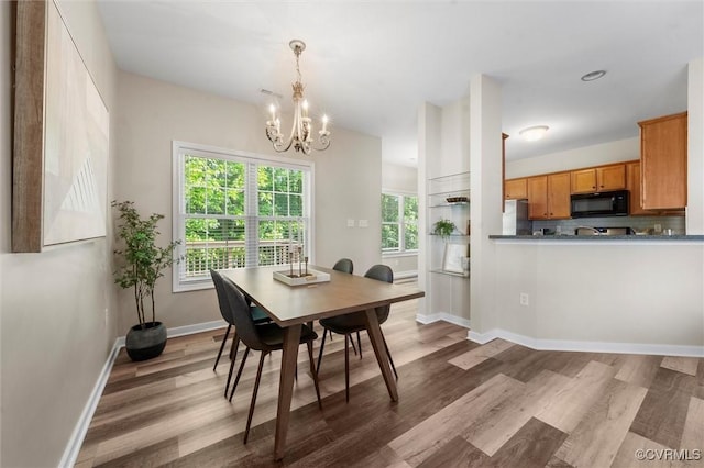 dining area with a chandelier, wood finished floors, and baseboards