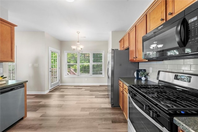kitchen with appliances with stainless steel finishes, a chandelier, brown cabinets, baseboards, and decorative backsplash